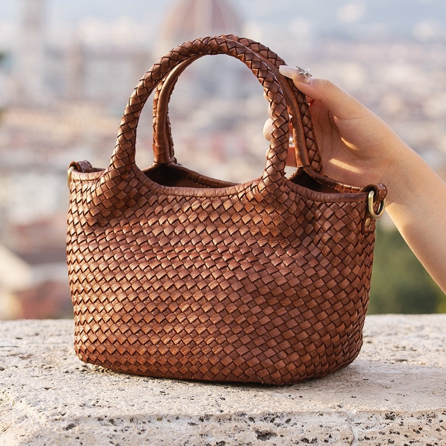 Geflochtene Ledertasche vor einer Stadtkulisse
